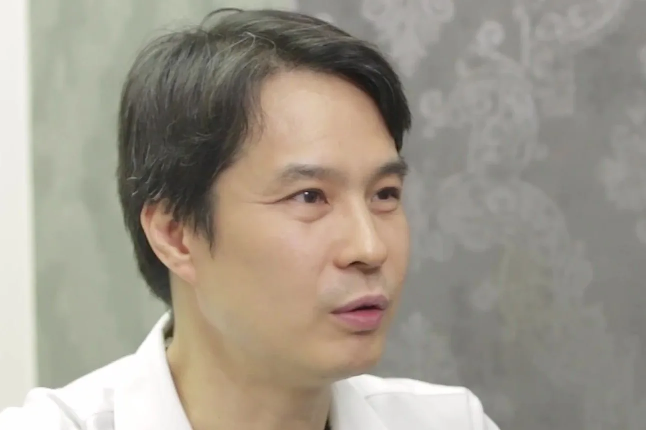 흰 가운을 입은 의사가 옆을 보며 이야기하는 모습