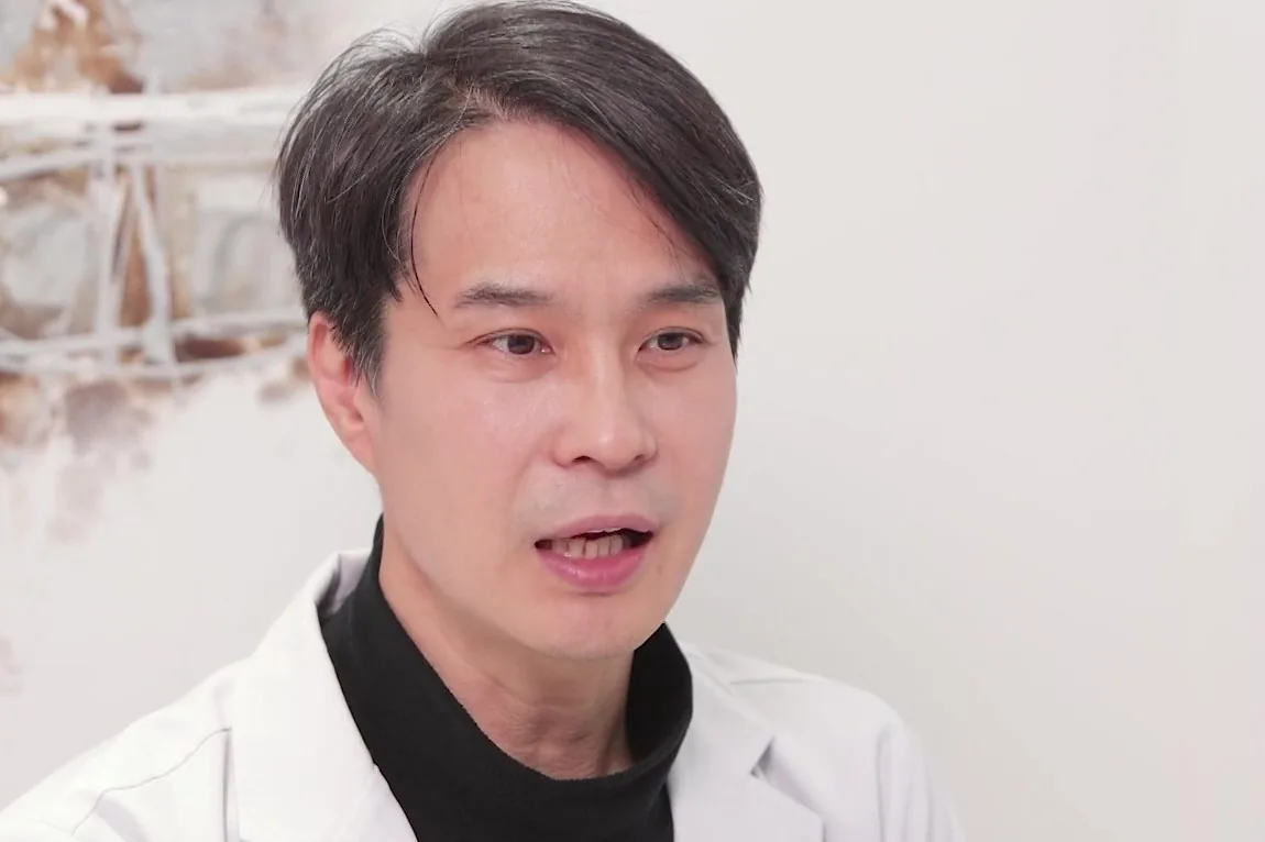 흰 가운을 입은 의사가 옆을 보며 말하는 모습